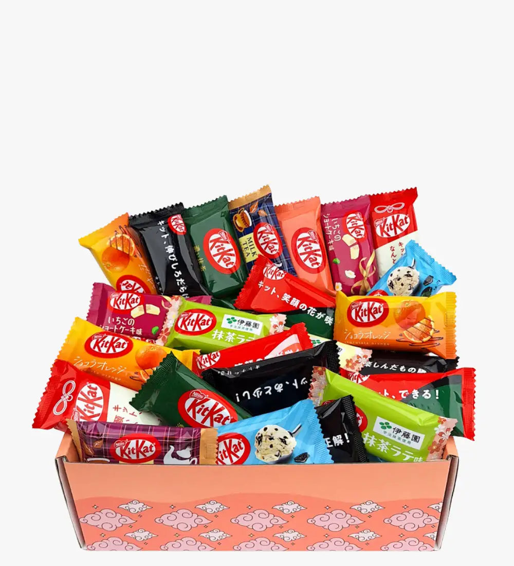Eine lebendige Auswahl an KitKat-Schokoladenriegeln in farbenfrohen, gemischten Verpackungen, die in einer rosa gemusterten Geschenkschachtel ruhen.