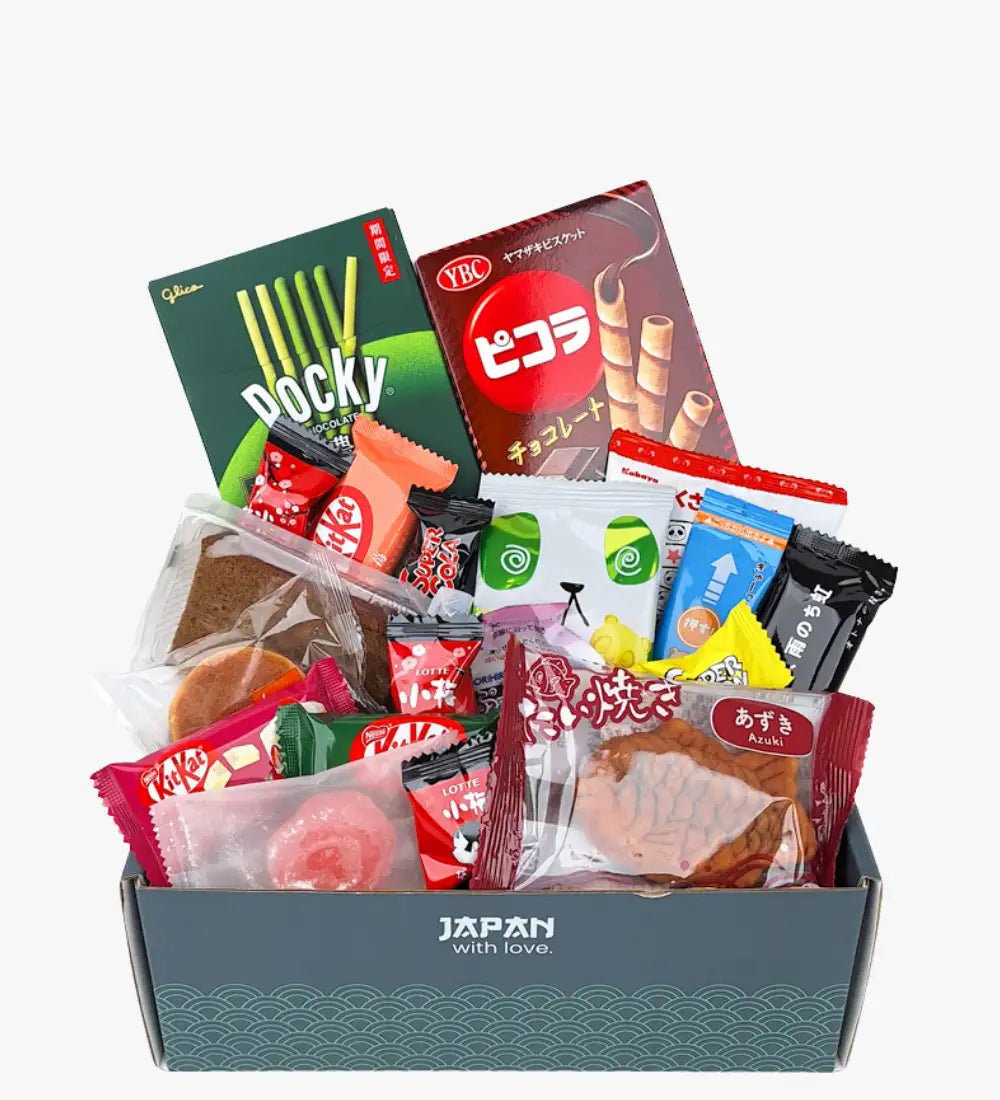 Eine graue Geschenkschachtel mit der Aufschrift „Japan with love“ gefüllt mit einer Auswahl japanischer Snacks, einschließlich Pocky, KitKat und Azuki-Keksen.