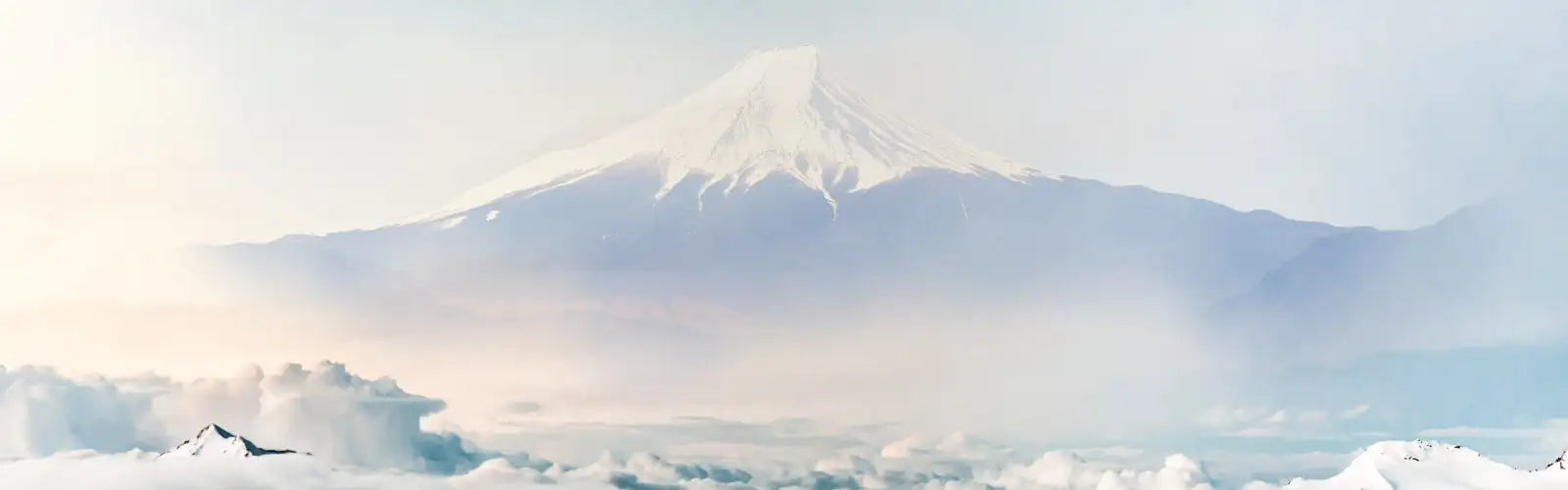 Schneebedeckter Mount Fuji erhebt sich majestätisch vor einem weichen, nebligen Himmel.